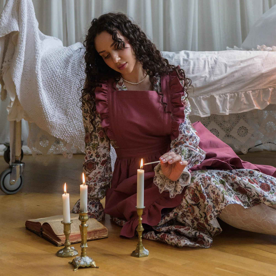 Woman in the dusty rose ruffle apron lighting candles