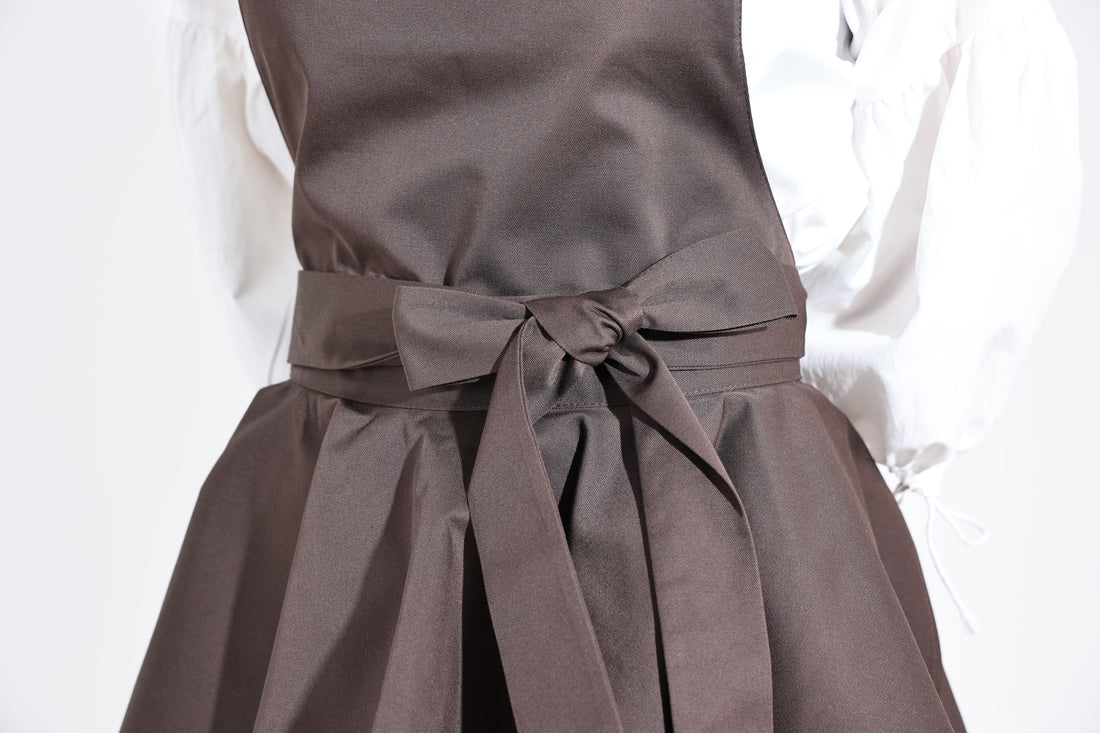Close-up of the waist bow and pleated ruffle on the dark brown apron