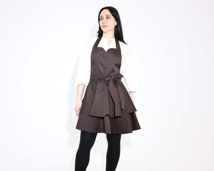Model wearing a dark brown Daisy ruffle apron with a two-tier skirt