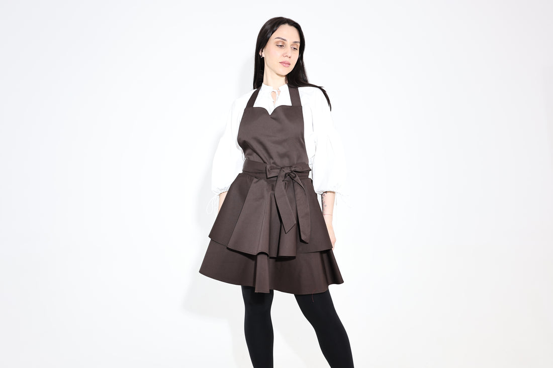 Dark brown ruffle apron worn over a white blouse, three-quarter view