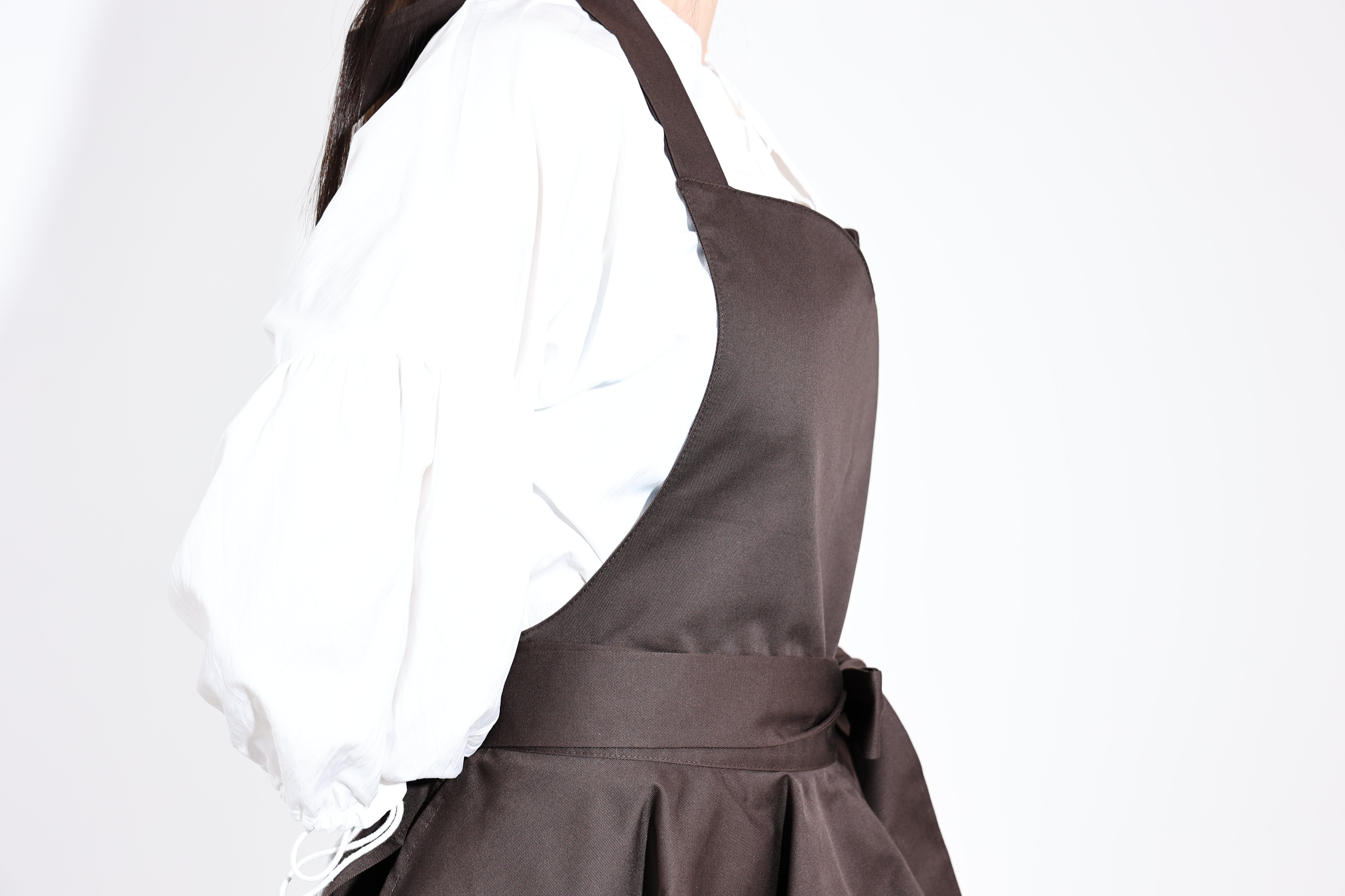 Side view of the dark brown apron showing the sweetheart bib and strap