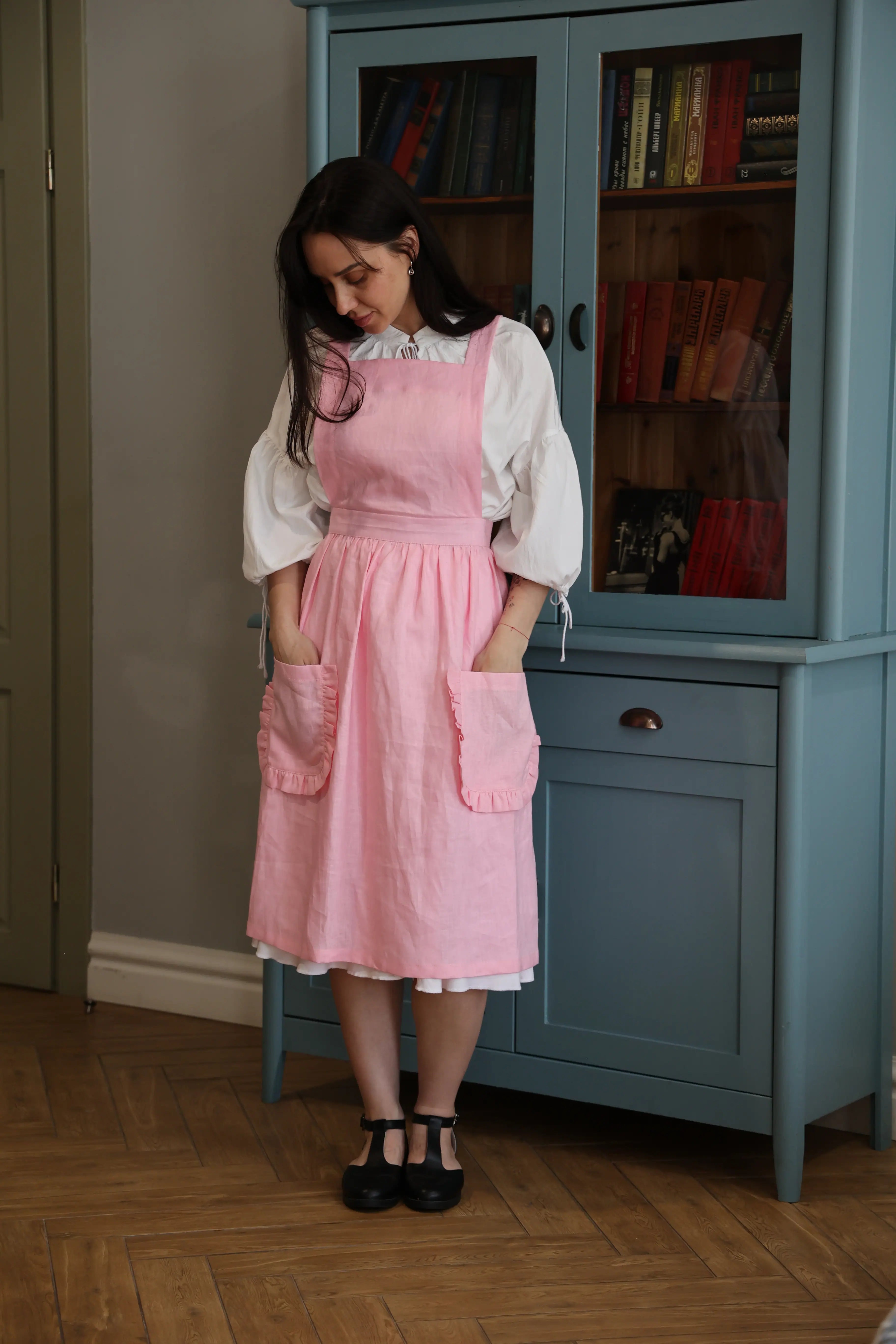 Woman with her hands in the pockets of the soft pink ruffle apron