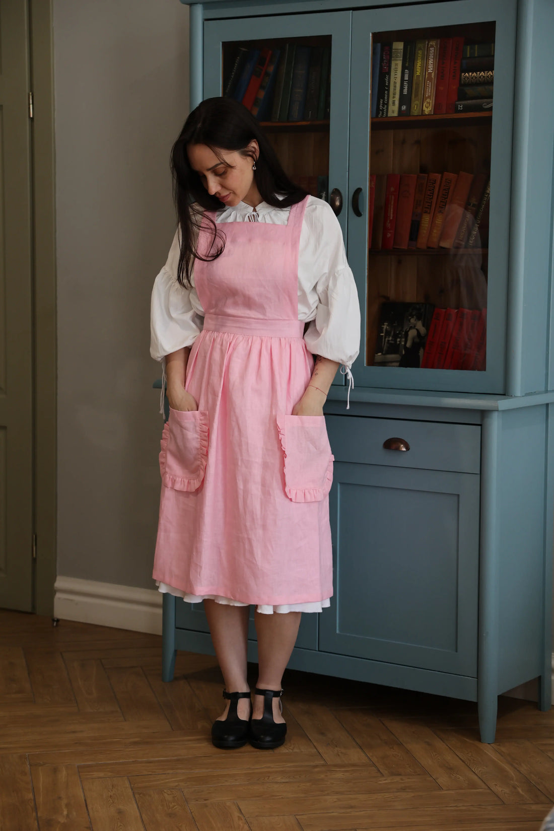 Woman with her hands in the pockets of the soft pink ruffle apron