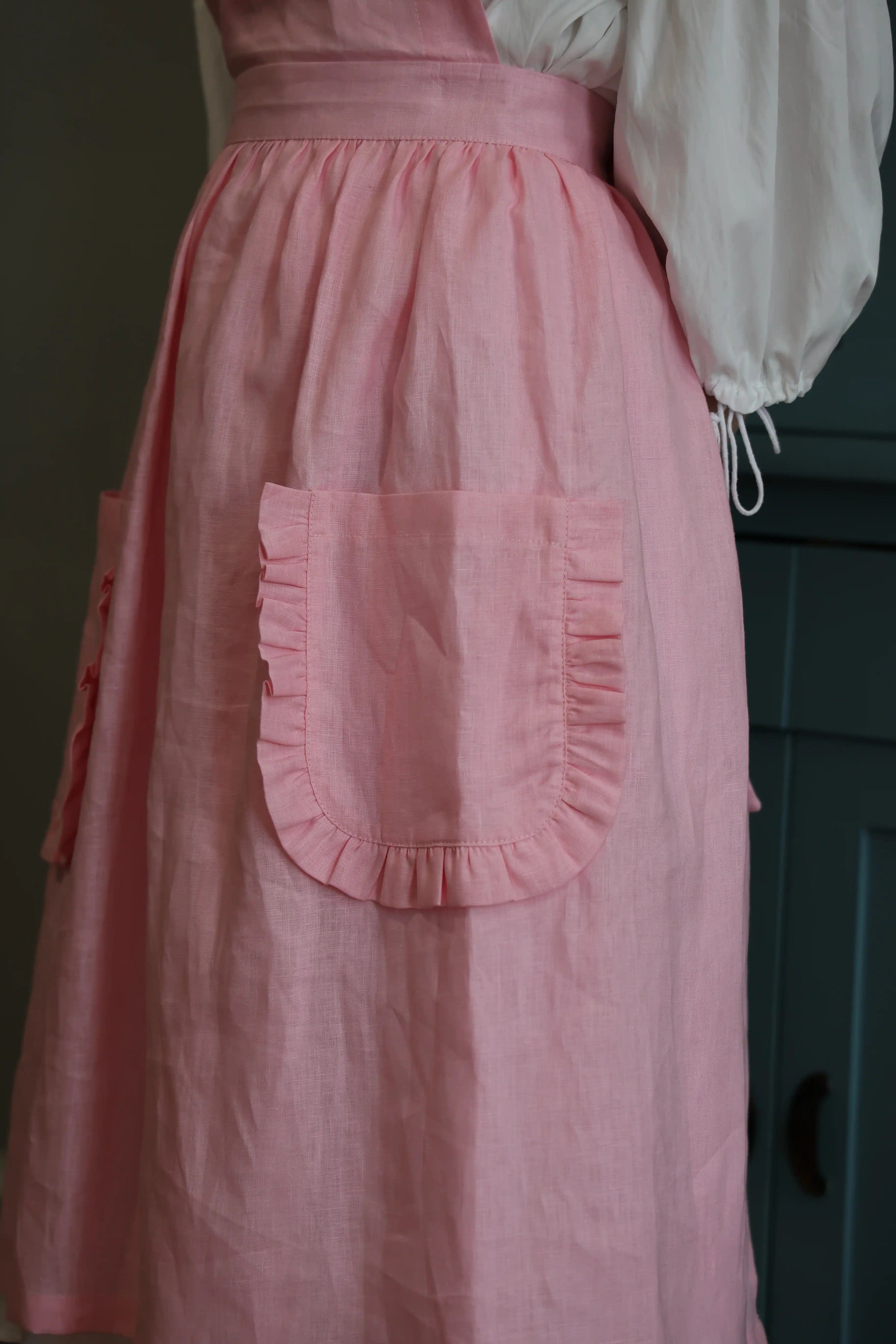 Close-up of the ruffled patch pocket on the soft pink apron