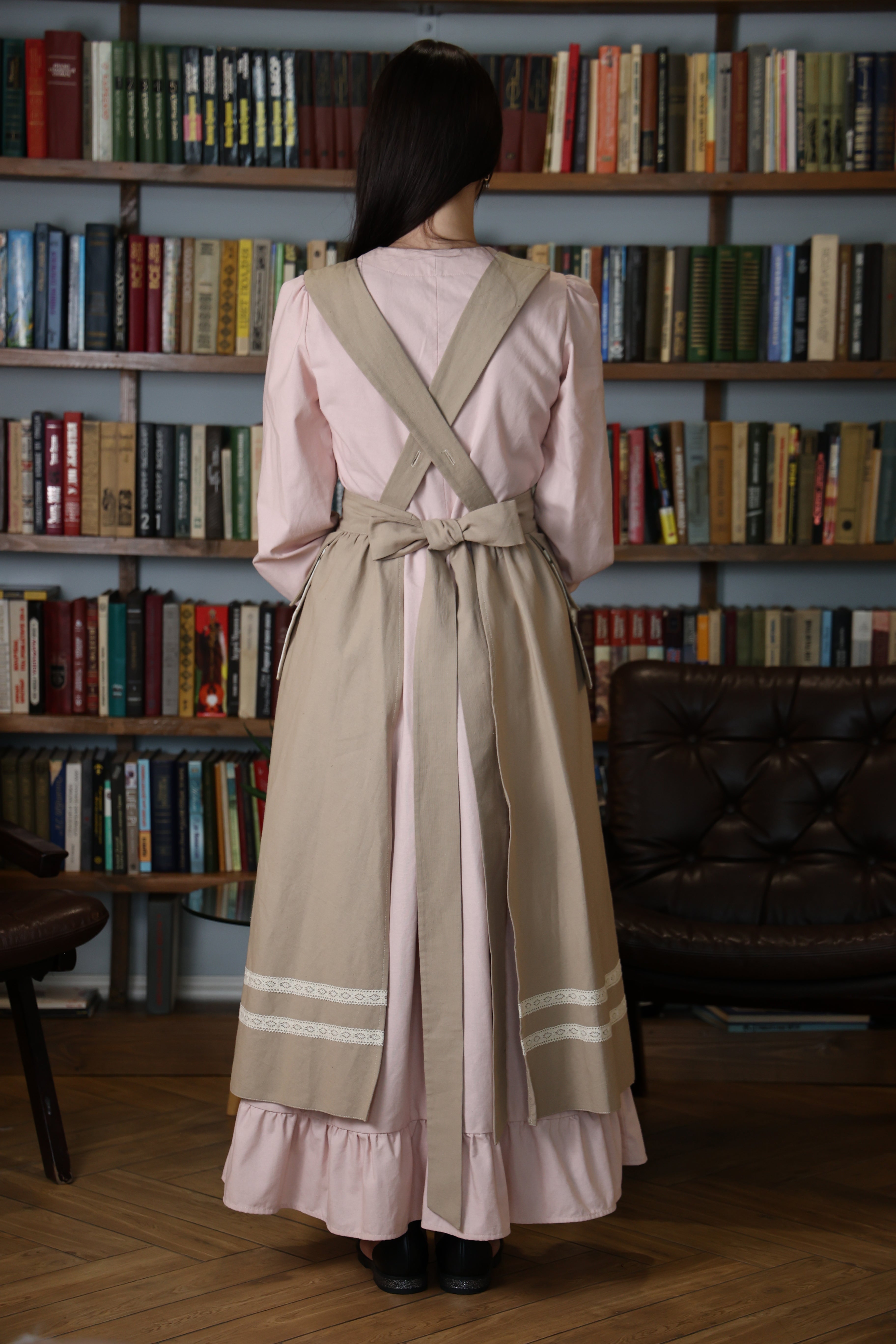 Back view of the beige pinafore apron with crossback straps tied in a bow