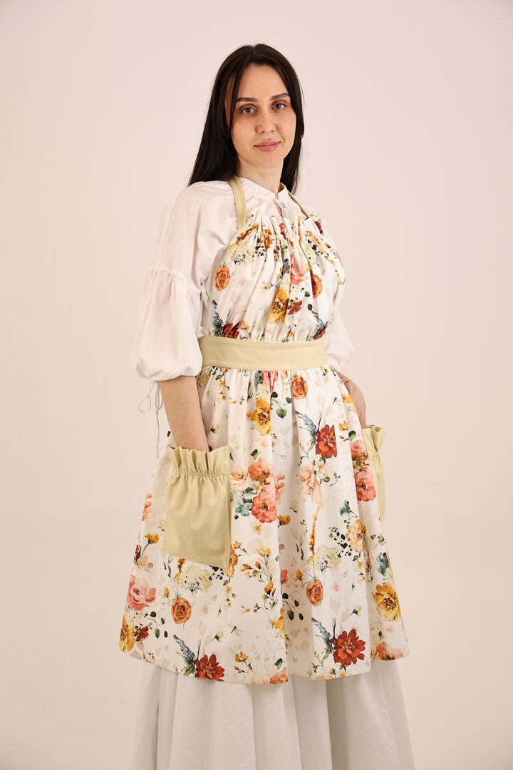 Woman wearing a floral dress with a yellow apron against a plain background