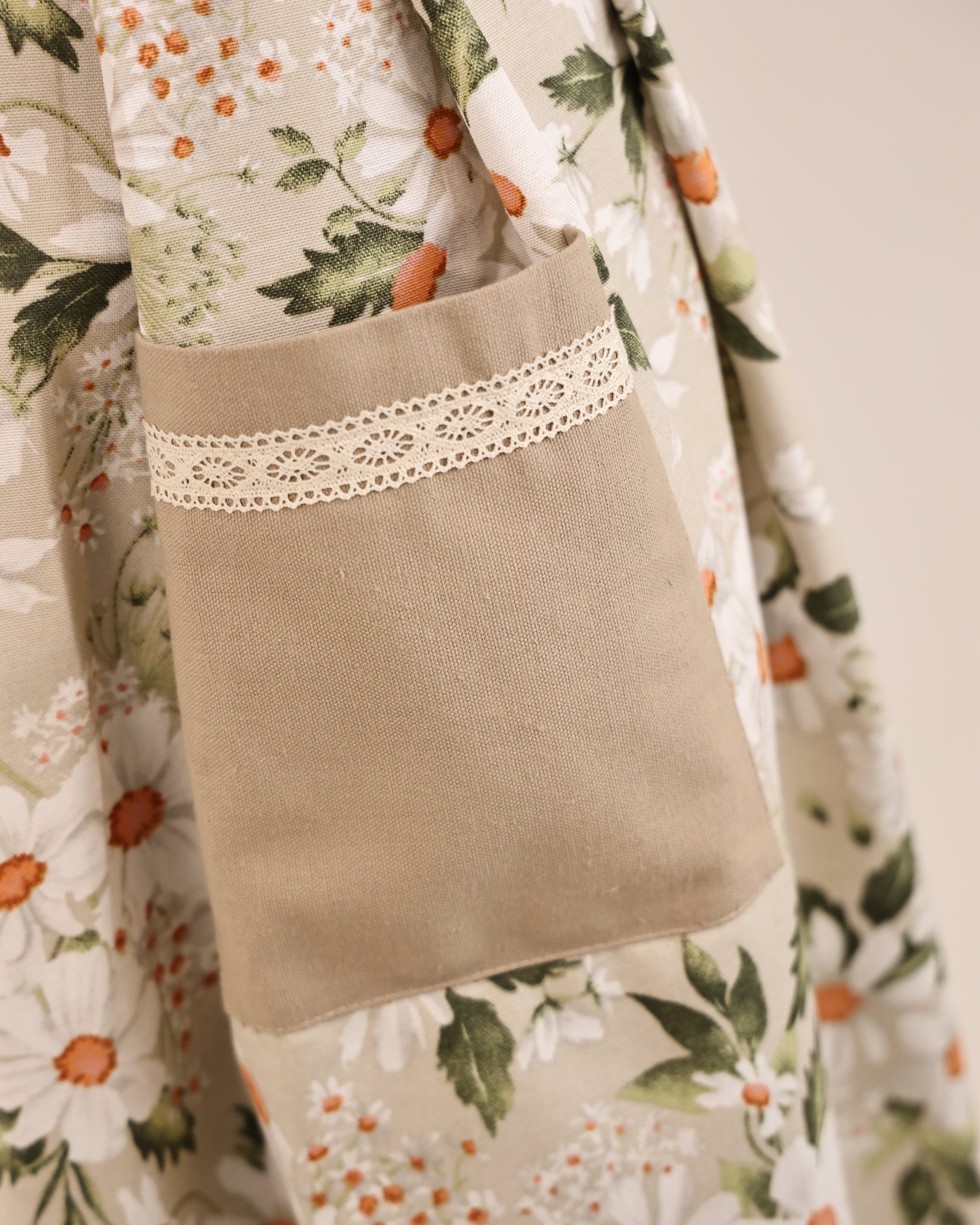 Floral-patterned fabric with a brown pillow featuring lace trim.