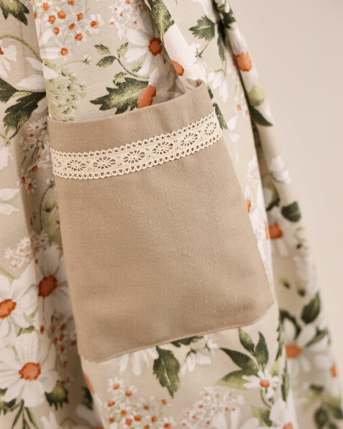 Floral-patterned fabric with a brown pillow featuring lace trim.