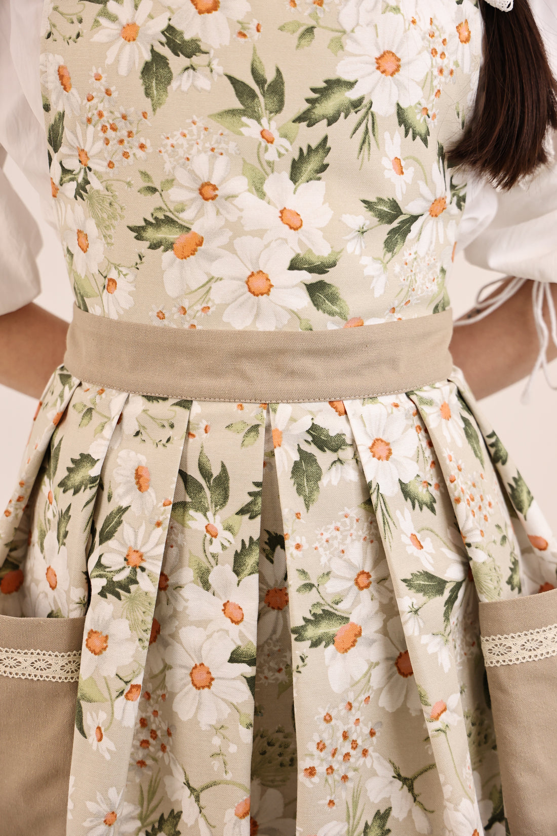 Floral apron with white flowers and green leaves on a beige background
