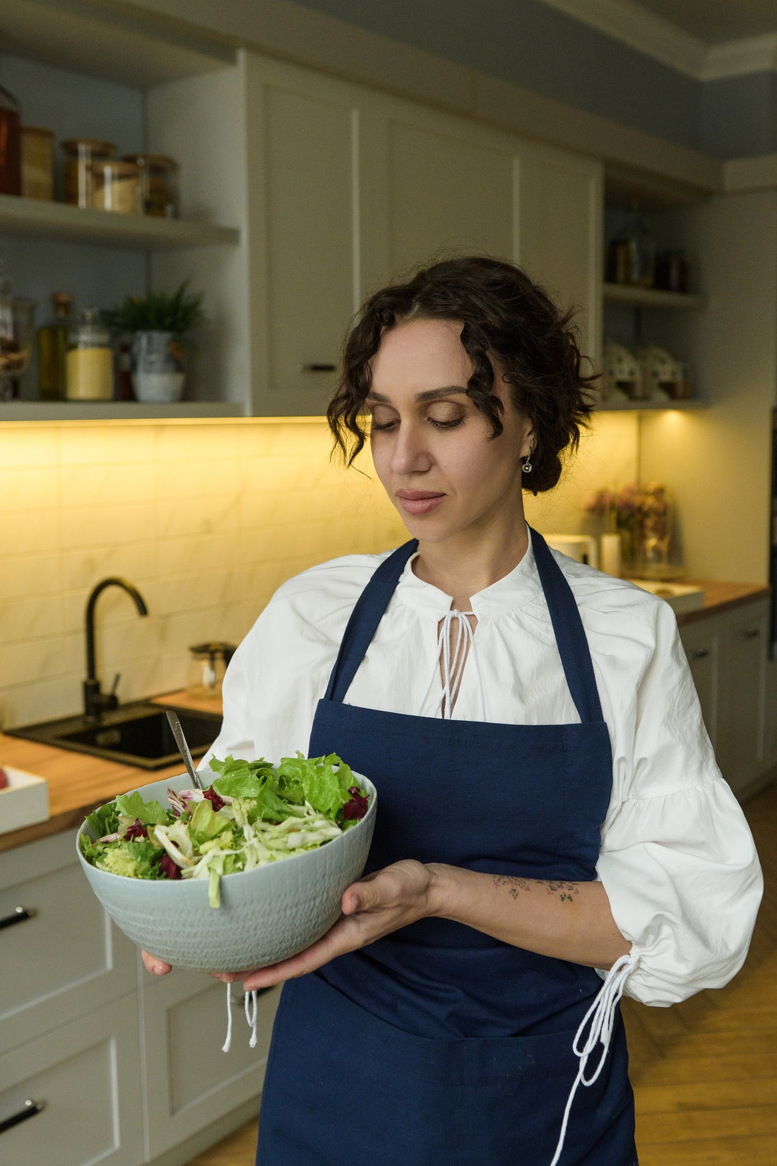 Navy blue cotton bib apron worn over a white blouse, front view