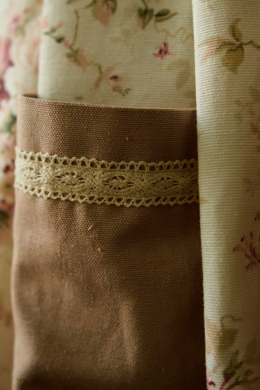 Close-up of a brown fabric with lace trim against a floral background