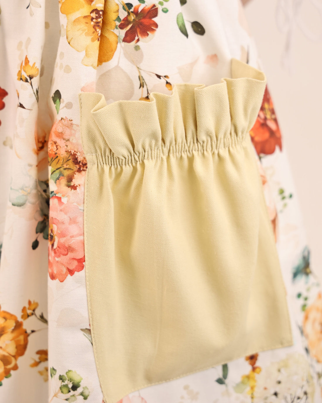 Yellow apron over a floral dress with a blurred background