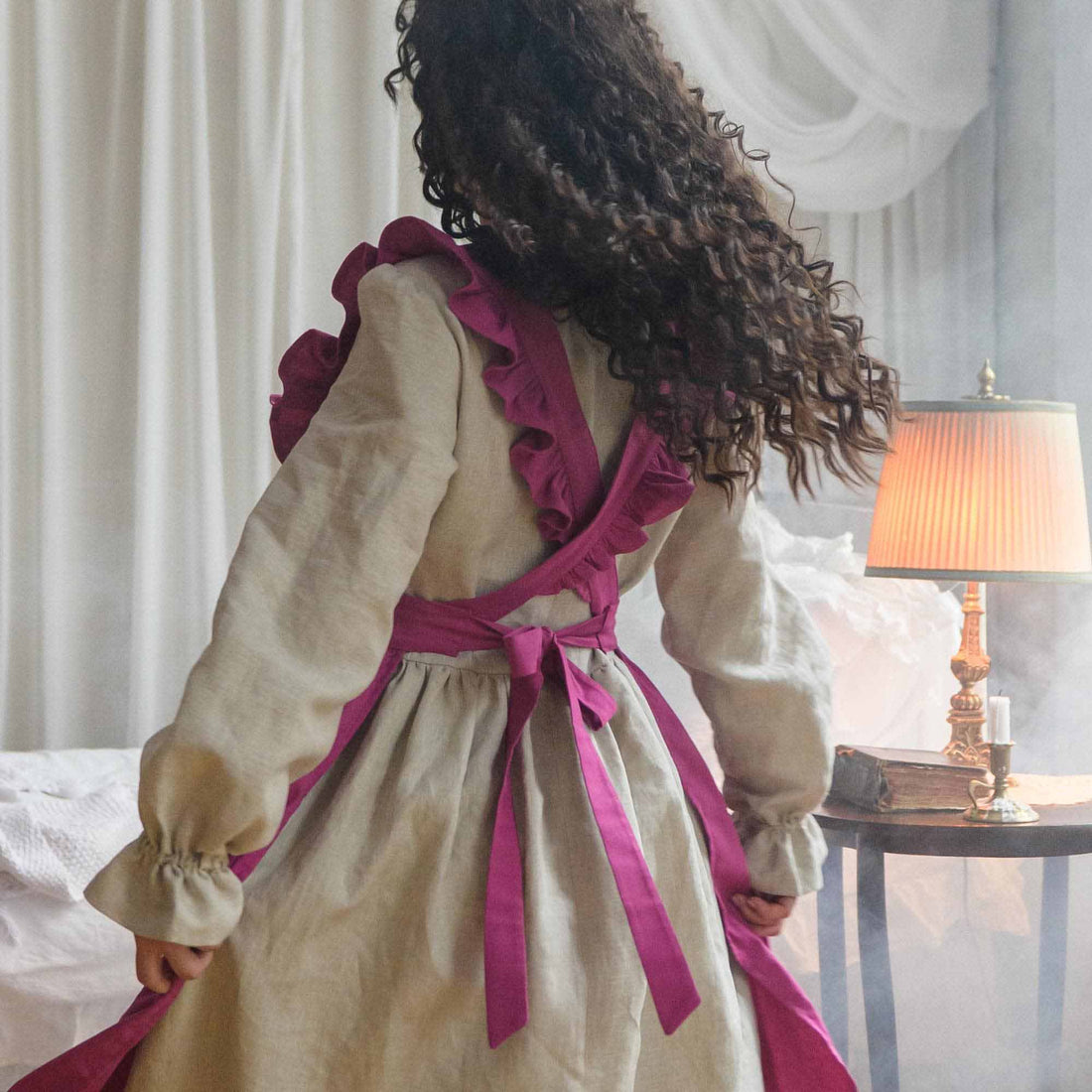 Person wearing a beige apron with pink accents in a bedroom setting