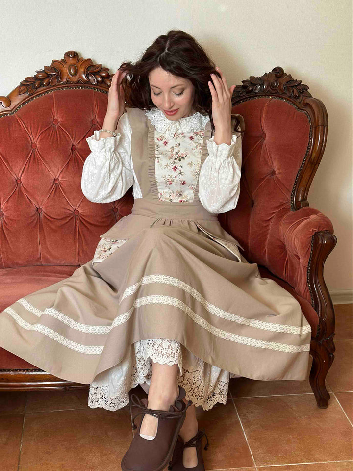 Woman in a vintage outfit sitting on an ornate red sofa.