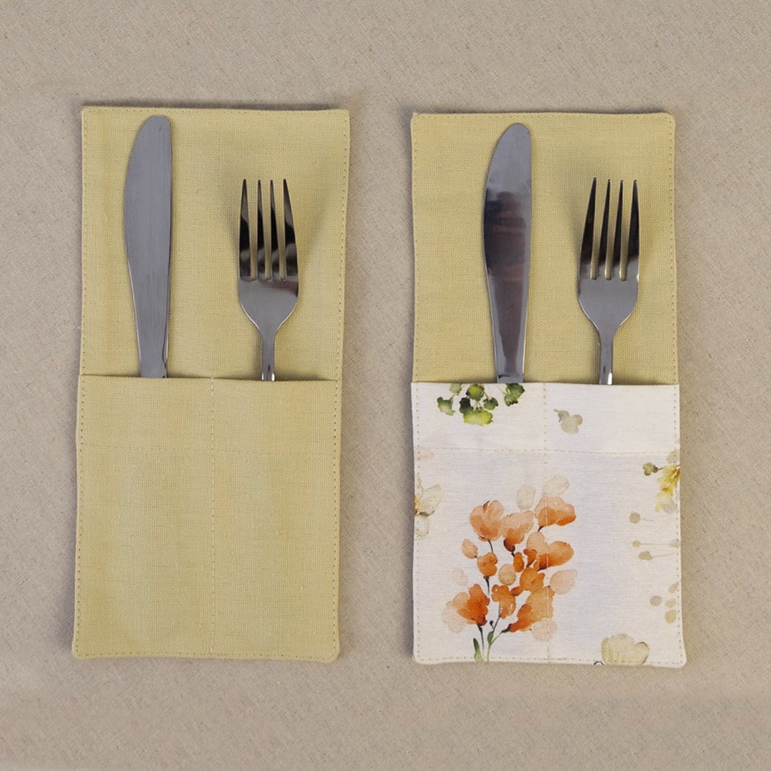 Two butter yellow cutlery pockets holding a knife and fork, one plain and one with a wildflower print panel