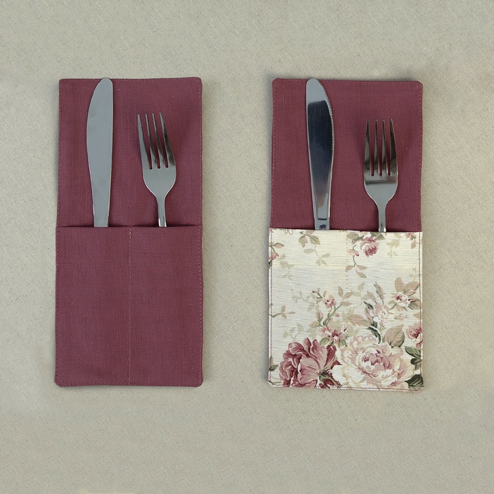 Two deep burgundy cutlery pockets holding a knife and fork, one plain and one with a rose print panel