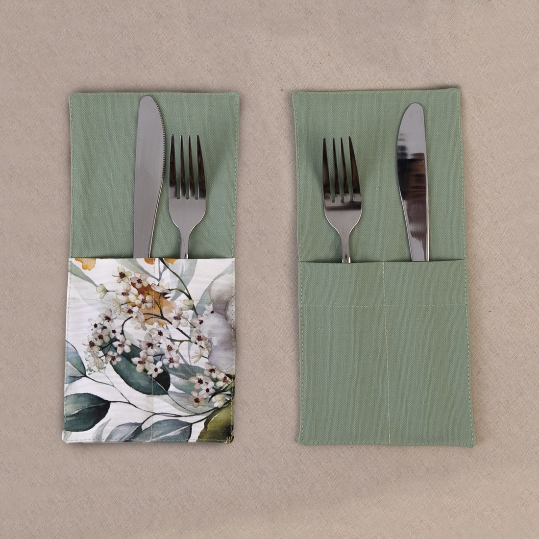 Two sage green cutlery pockets holding a knife and fork, one plain and one with a eucalyptus print panel
