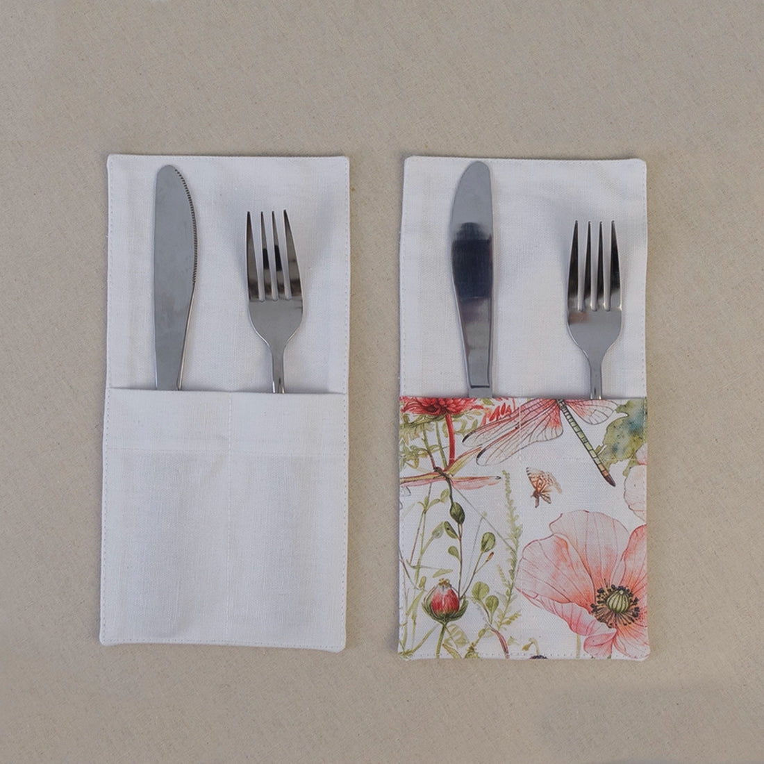 Two soft white cutlery pockets holding a knife and fork, one plain and one with a poppy print panel