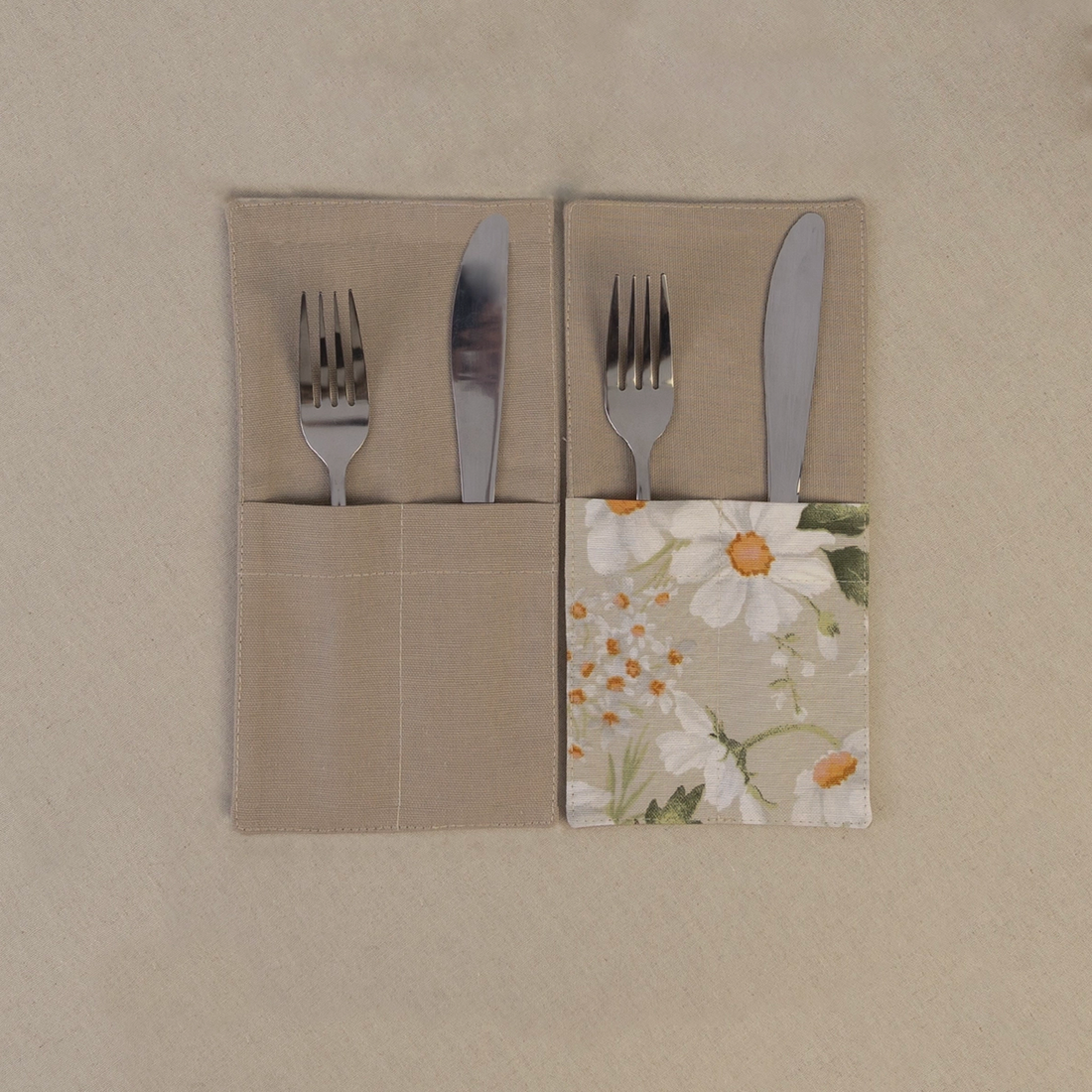 Two taupe beige cutlery pockets holding a knife and fork, one plain and one with a daisy print panel