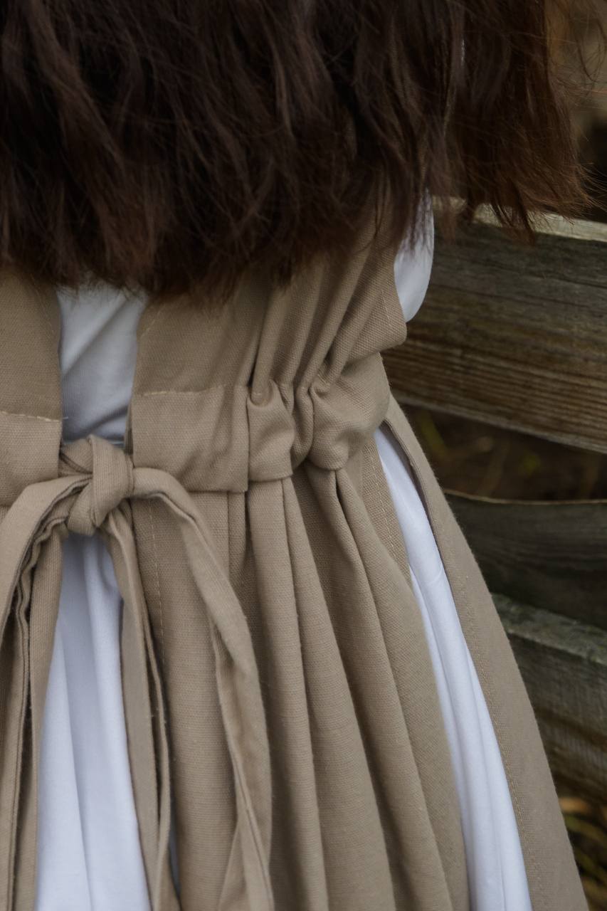 Close-up of a brown coat with a white shirt underneath, against a wooden background.