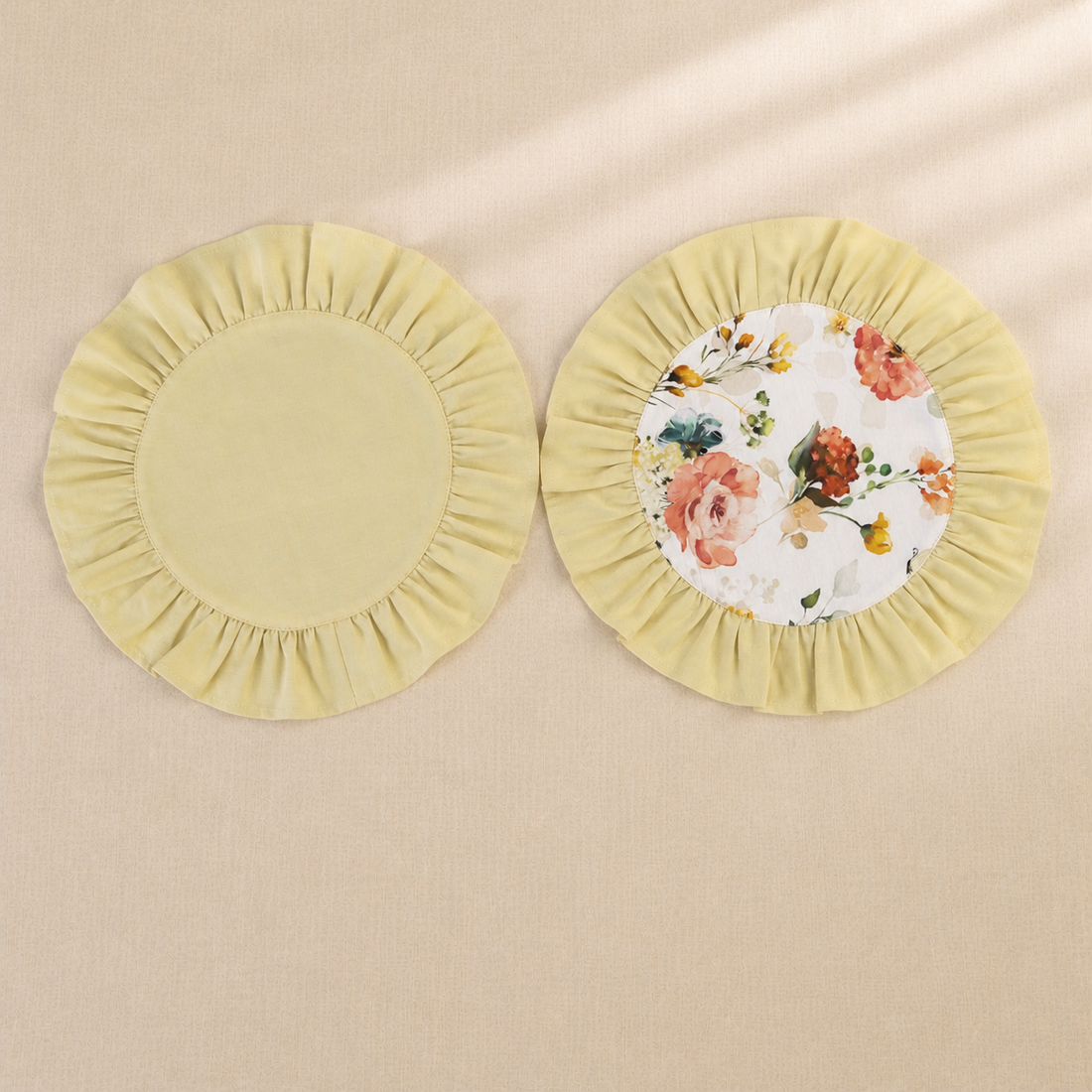 Two round butter yellow ruffle placemats, one plain and one with a peach rose print centre