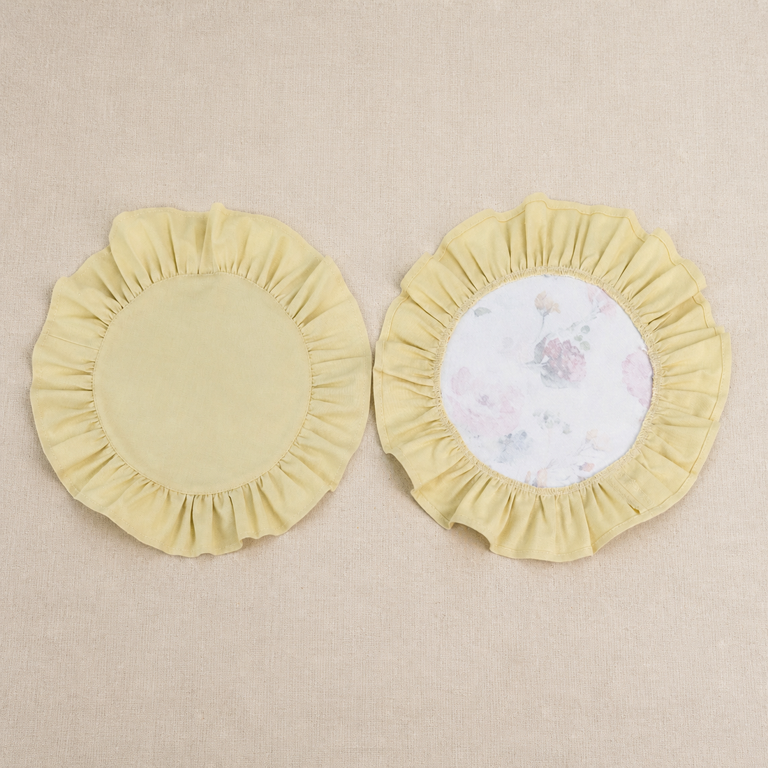 Two round butter yellow ruffle placemats, one plain and one with a white centre panel