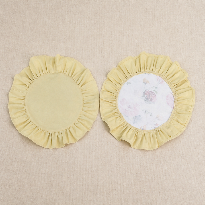 Two round butter yellow ruffle placemats, one plain and one with a white centre panel