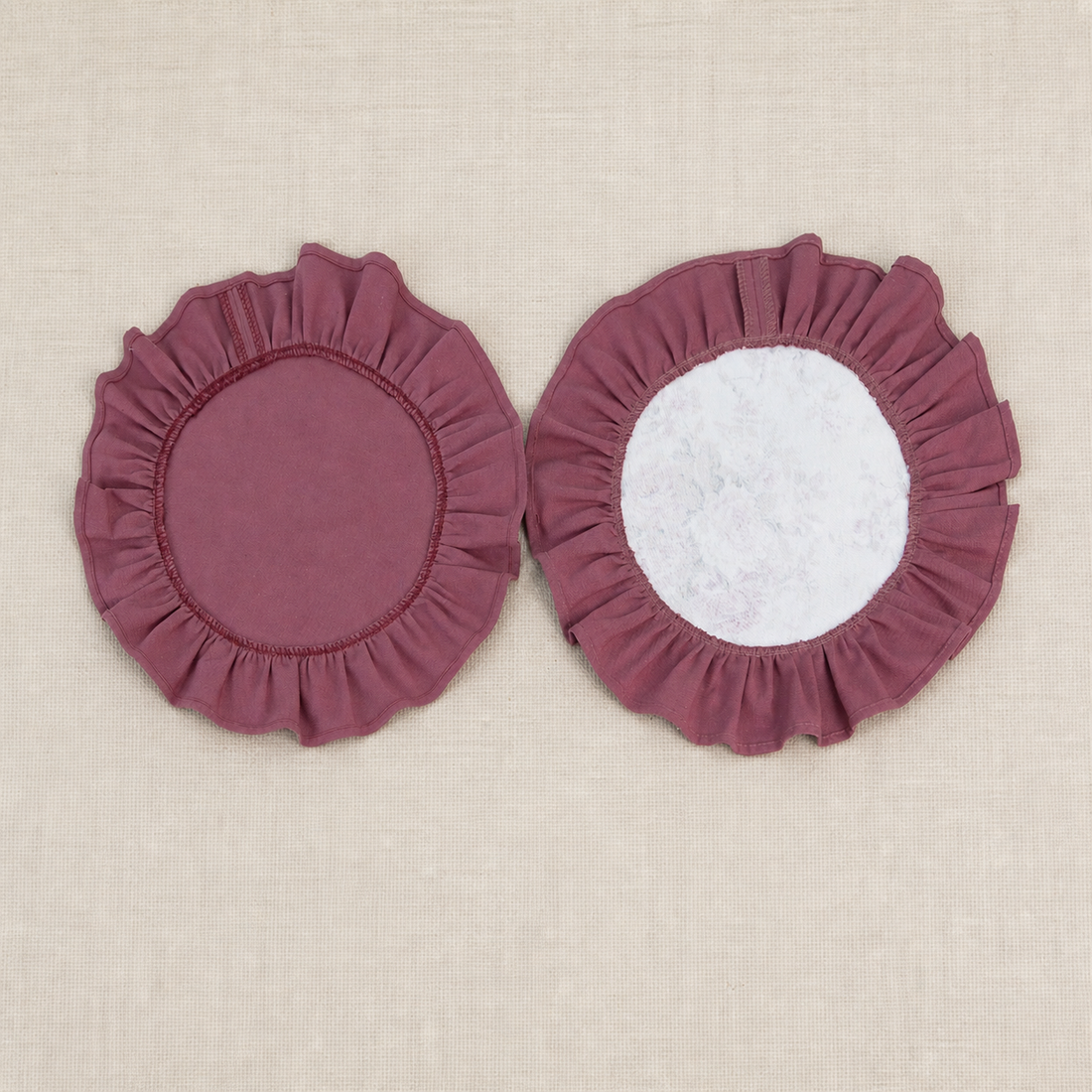Two round deep burgundy ruffle placemats, one plain and one with a white centre panel