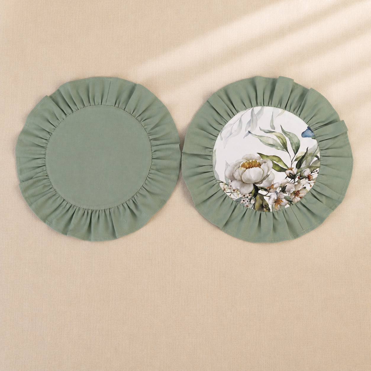 Two round sage green ruffle placemats, one plain and one with a peony and eucalyptus print centre