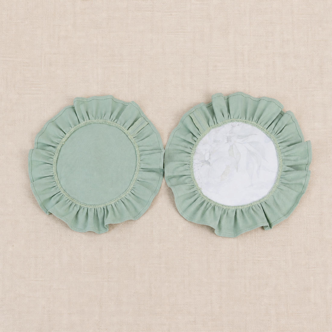 Two round sage green ruffle placemats, one plain and one with a white centre panel