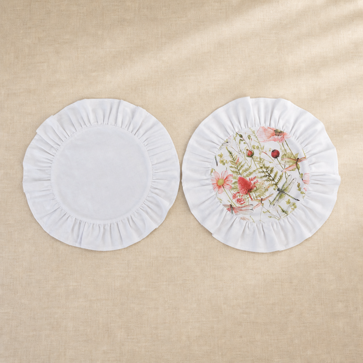 Two round soft white ruffle placemats, one plain and one with a pink poppy print centre