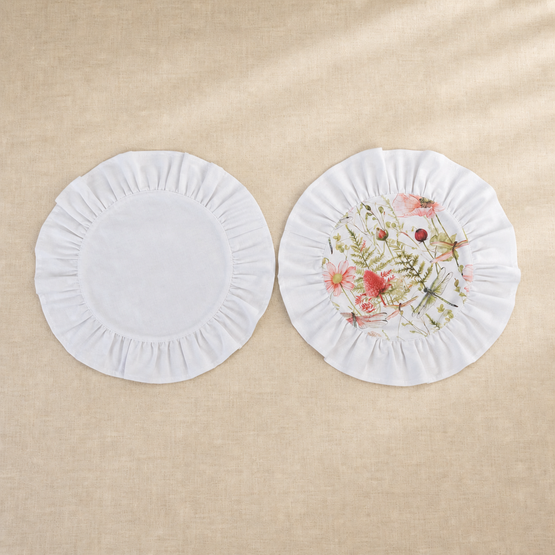 Two round soft white ruffle placemats, one plain and one with a pink poppy print centre