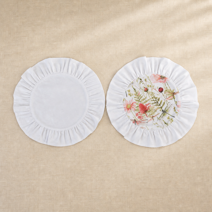 Two round soft white ruffle placemats, one plain and one with a pink poppy print centre