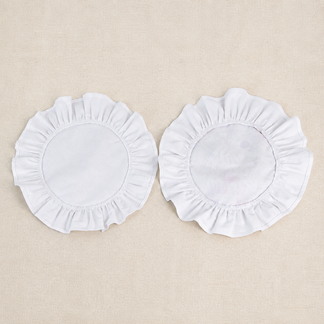 Two round soft white ruffle placemats, one plain and one with a white centre panel
