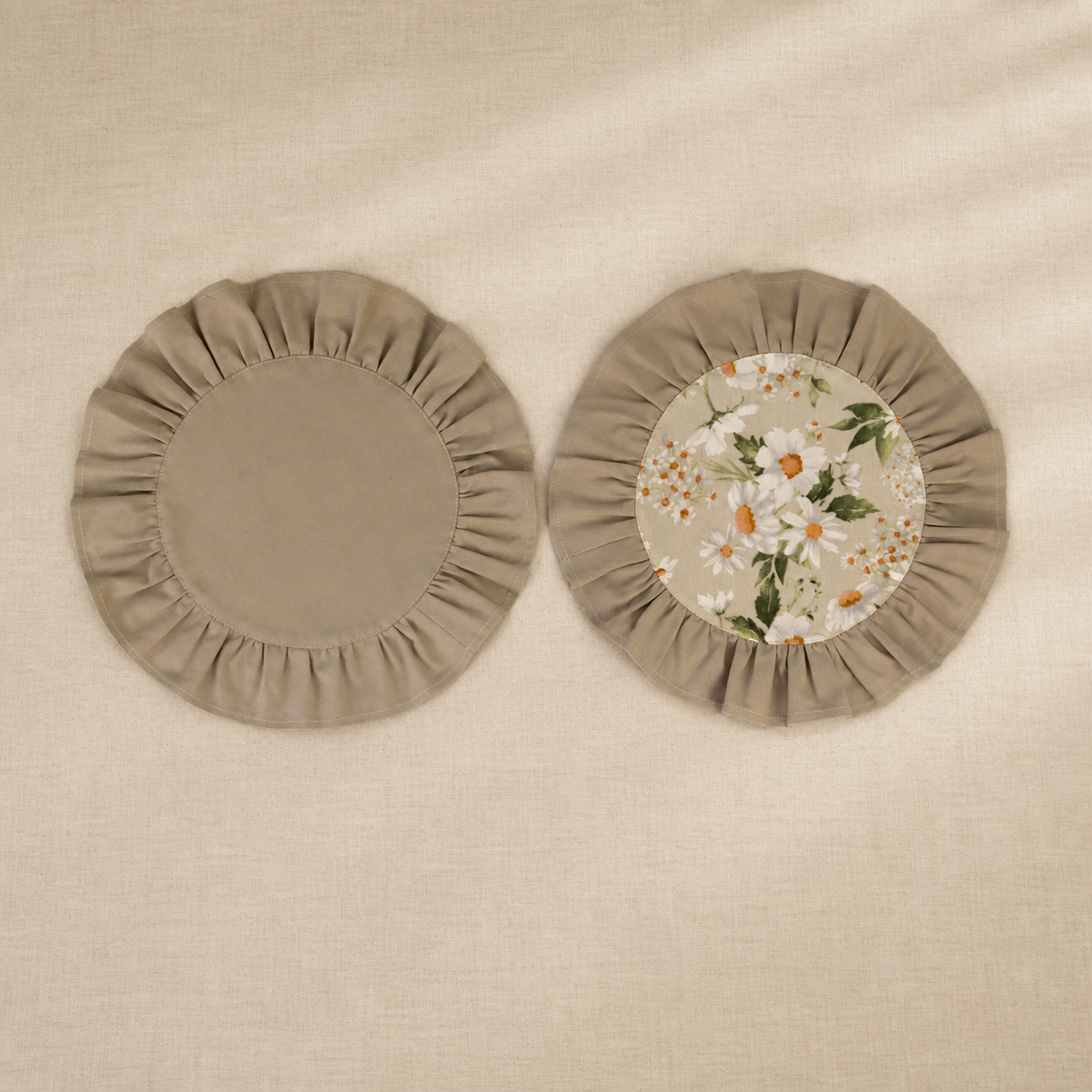 Two round taupe beige ruffle placemats, one plain and one with a daisy print centre