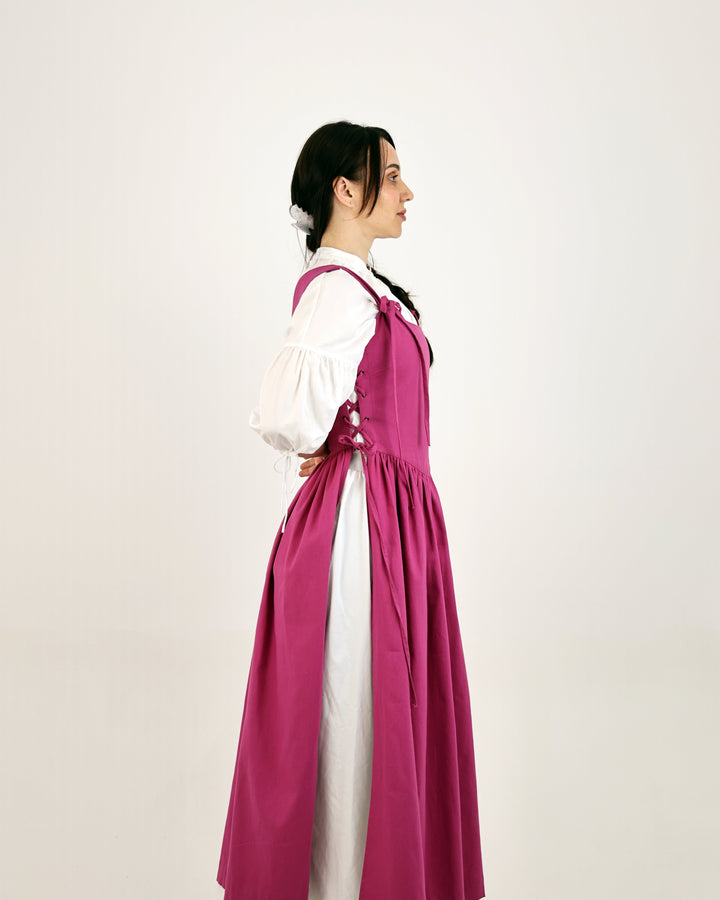 Woman wearing a long pink cotton with a white blouse on a plain background
