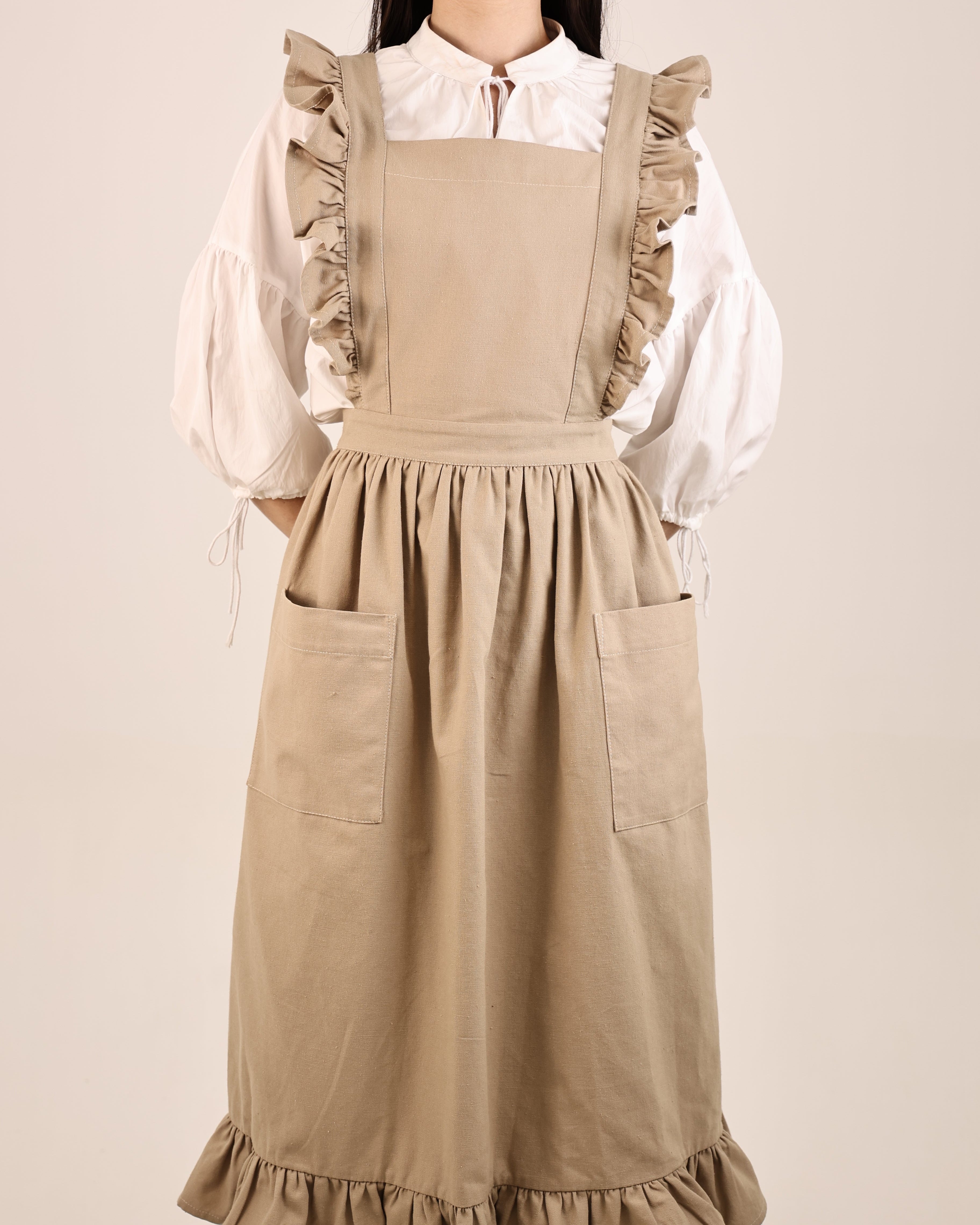 Person wearing a beige apron over a white blouse on a plain background