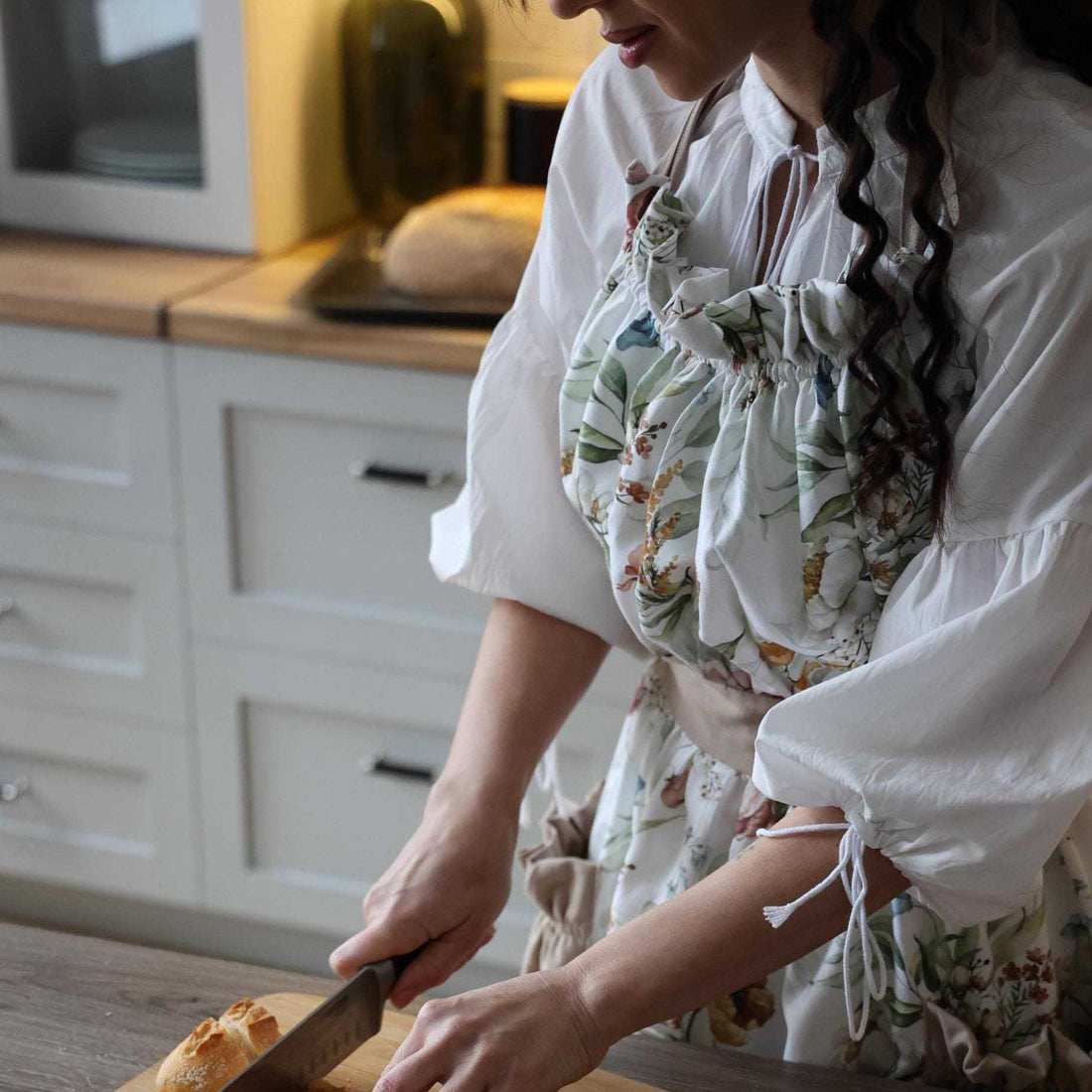 Person in a kitchen cutting bread on a wooden board