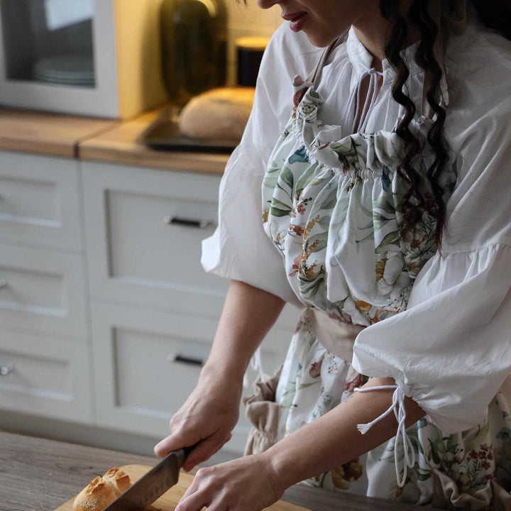 Person in a kitchen cutting bread on a wooden board