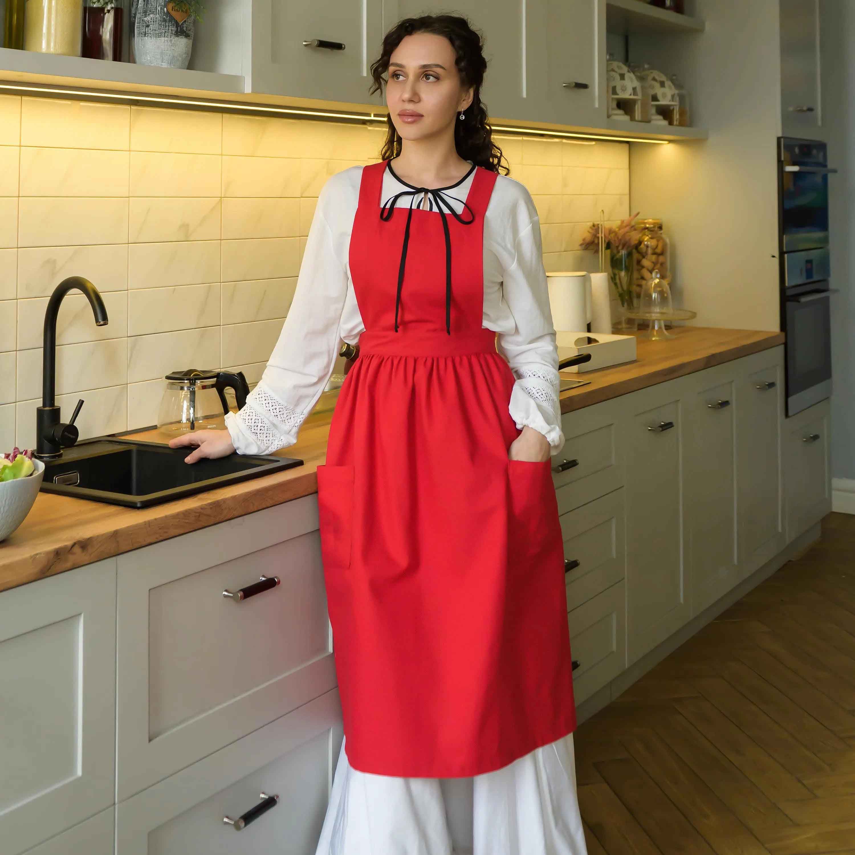 Woman in a red apron standing in a kitchen.