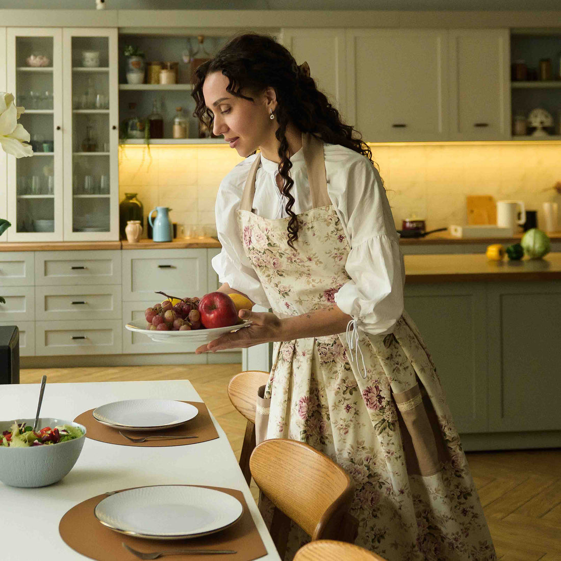 Woman in a kitchen holding a plate with fruit, standing near a dining table.