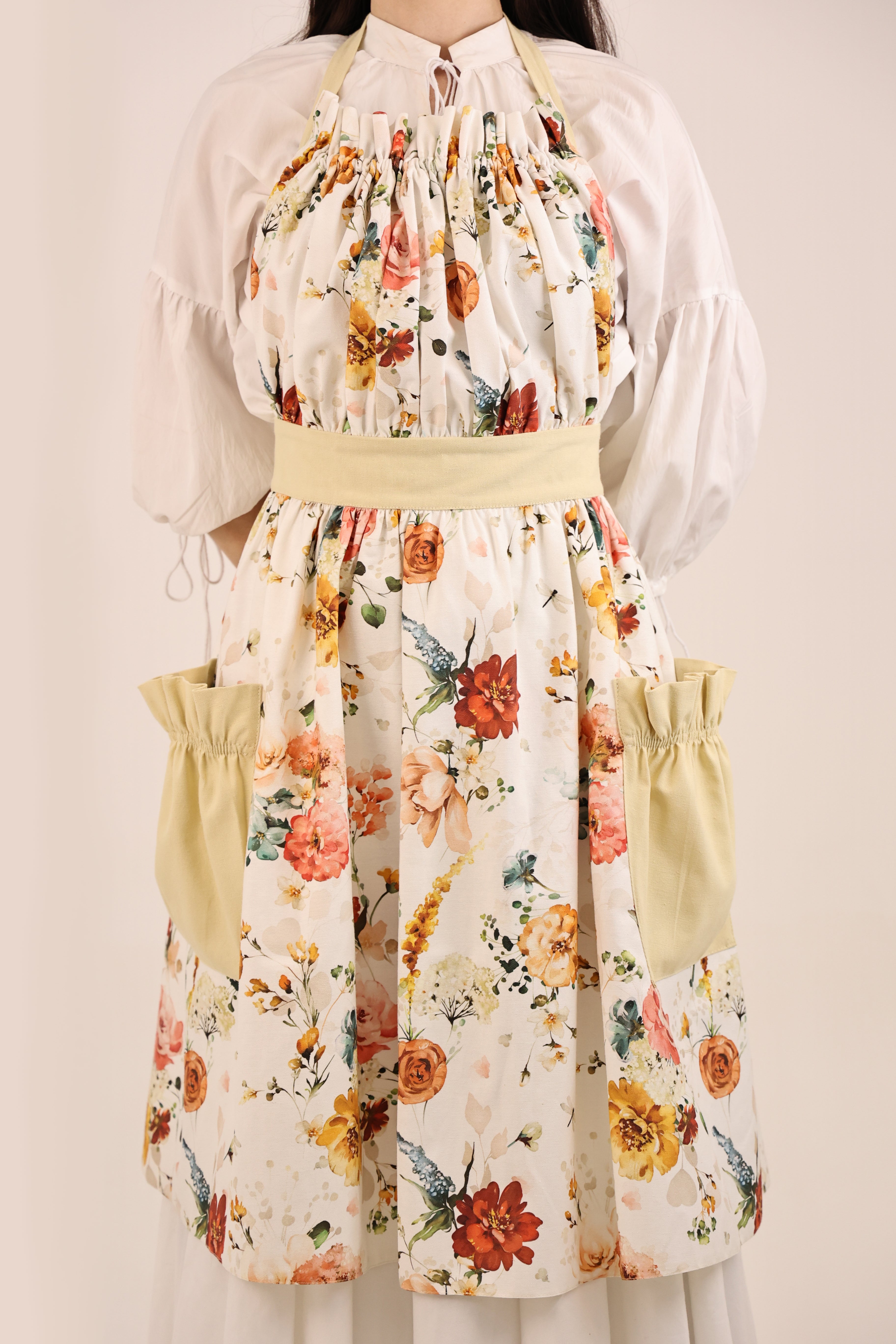 Person wearing a floral apron with a plain background