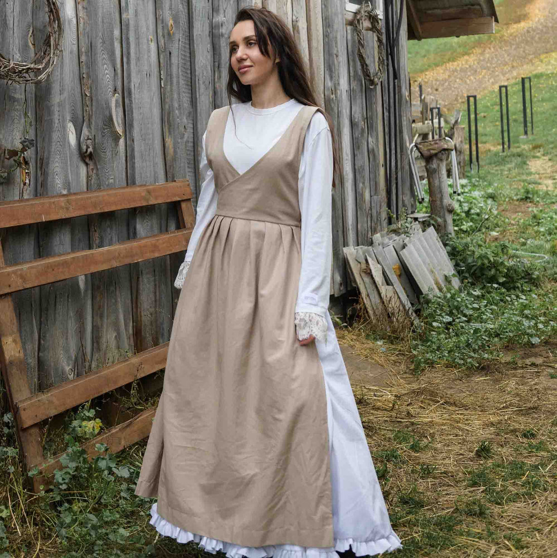Woman in a historical dress standing in front of a wooden building.